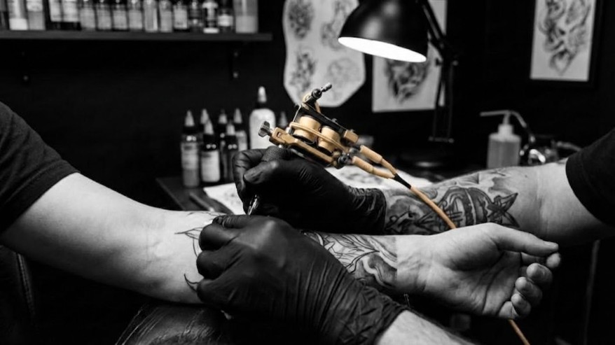 Tattoo artist working on a client's arm in a vibrant Boracay tattoo shop, showcasing creativity and skill.