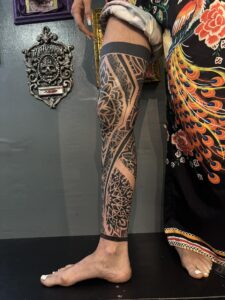 A full-leg sleeve tattoo featuring intricate blackwork geometric patterns