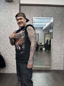 Full-arm realism sleeve tattoo in black and grey, featuring a stairway to heaven with a dove, a boombox with money, and the word 'Believe' on the hand.