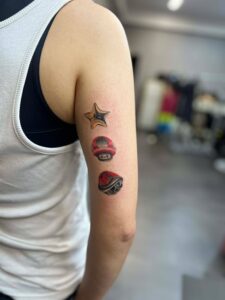 A person's arm features three small, colorful tattoos: a Super Star, a Super Mushroom, and a Koopa Shell, arranged vertically.