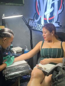 Valerie Concepcion featuring a delicate script and infinity symbol tattoo on her inner forearm by artist Kurt Bayeta, highlighting professional fine-line work in a premium Boracay studio.