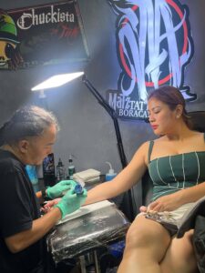 Valerie Concepcion featuring a delicate script and infinity symbol tattoo on her inner forearm by artist Kurt Bayeta, highlighting professional fine-line work in a premium Boracay studio.