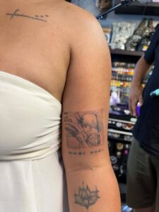A person's arm with a black and white tattoo of a scene from "Spirited Away" with the text "WABI SABI" below it.