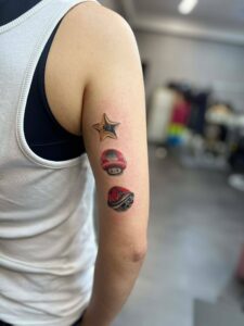 A person's arm features three small, colorful tattoos: a Super Star, a Super Mushroom, and a Koopa Shell, arranged vertically.